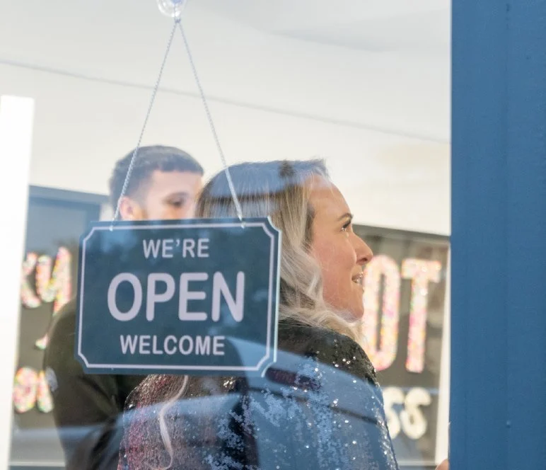 Guests behind a We are Open sign on the gallery door