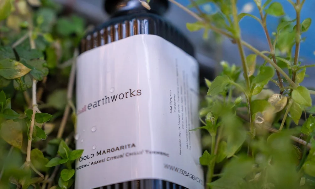 Earthworks Gold Margarita bottle among green plants