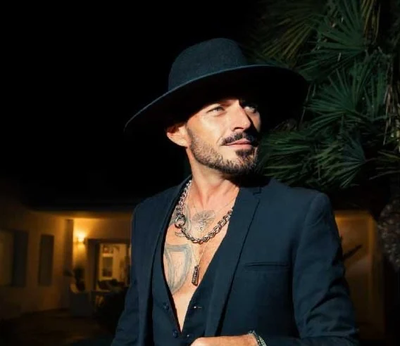Guest in a black hat and suit at night outside the villa