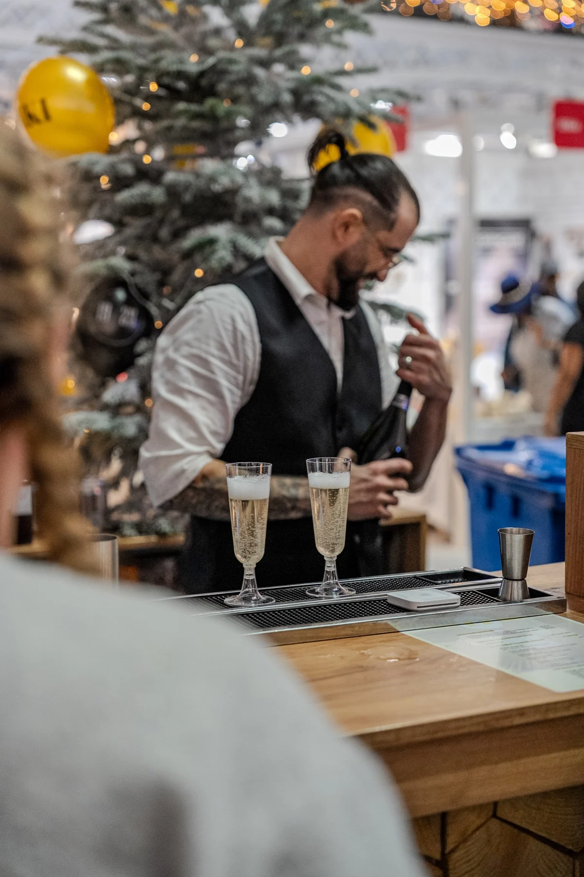A bartender in a waistcoat pouring drinks into flutes