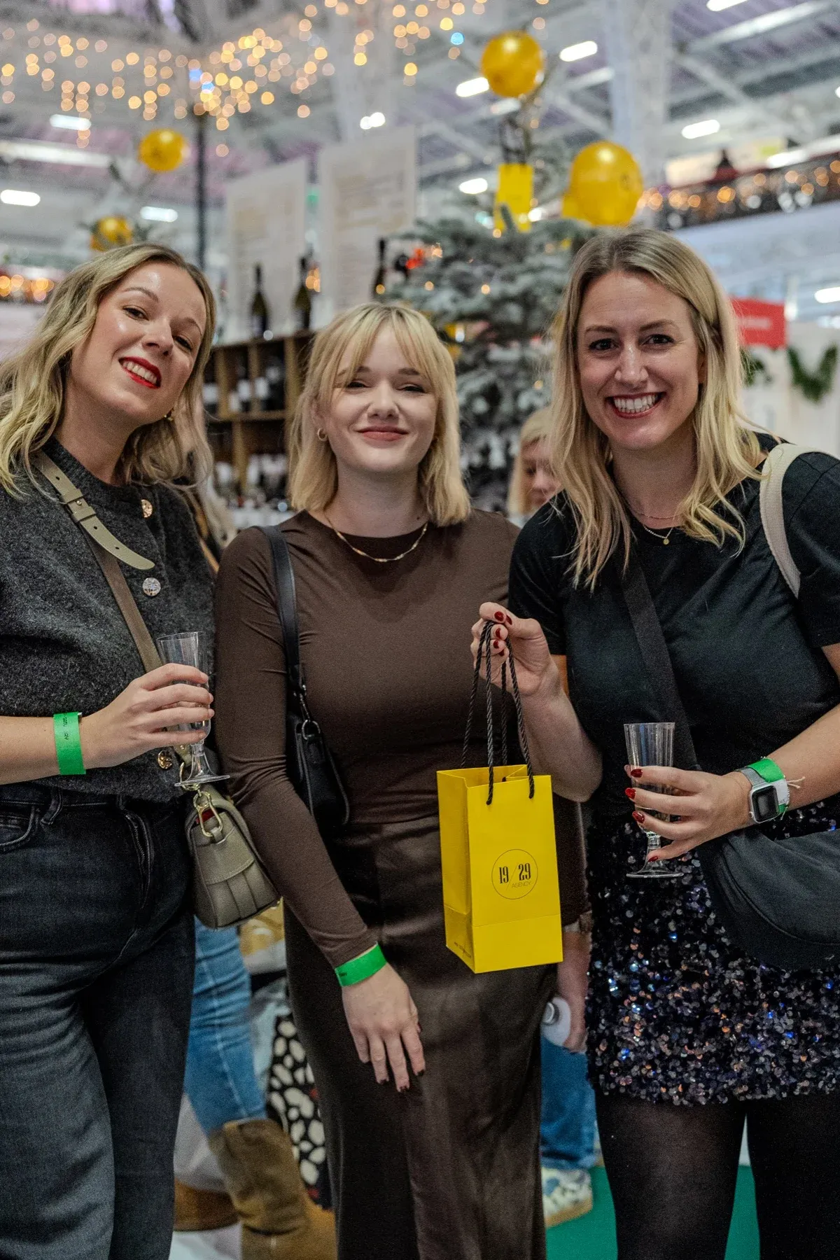 Three guests with drinks and a yellow 19/29 gift bag