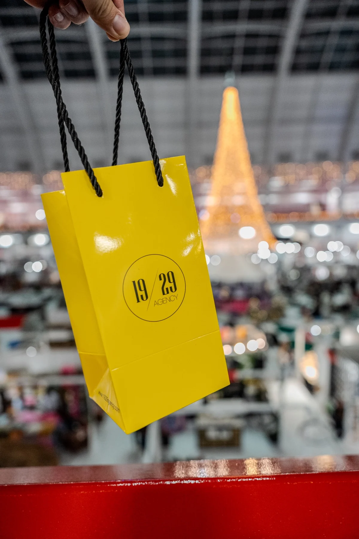A yellow 19/29 gift bag held up in the Olympia hall