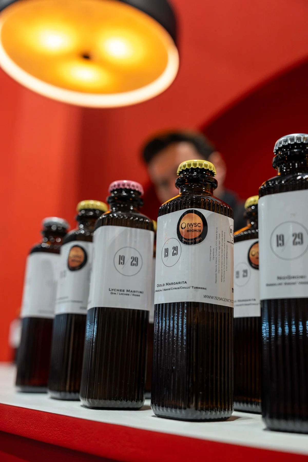 A row of 19/29 bottles on the red bar under a pendant lamp