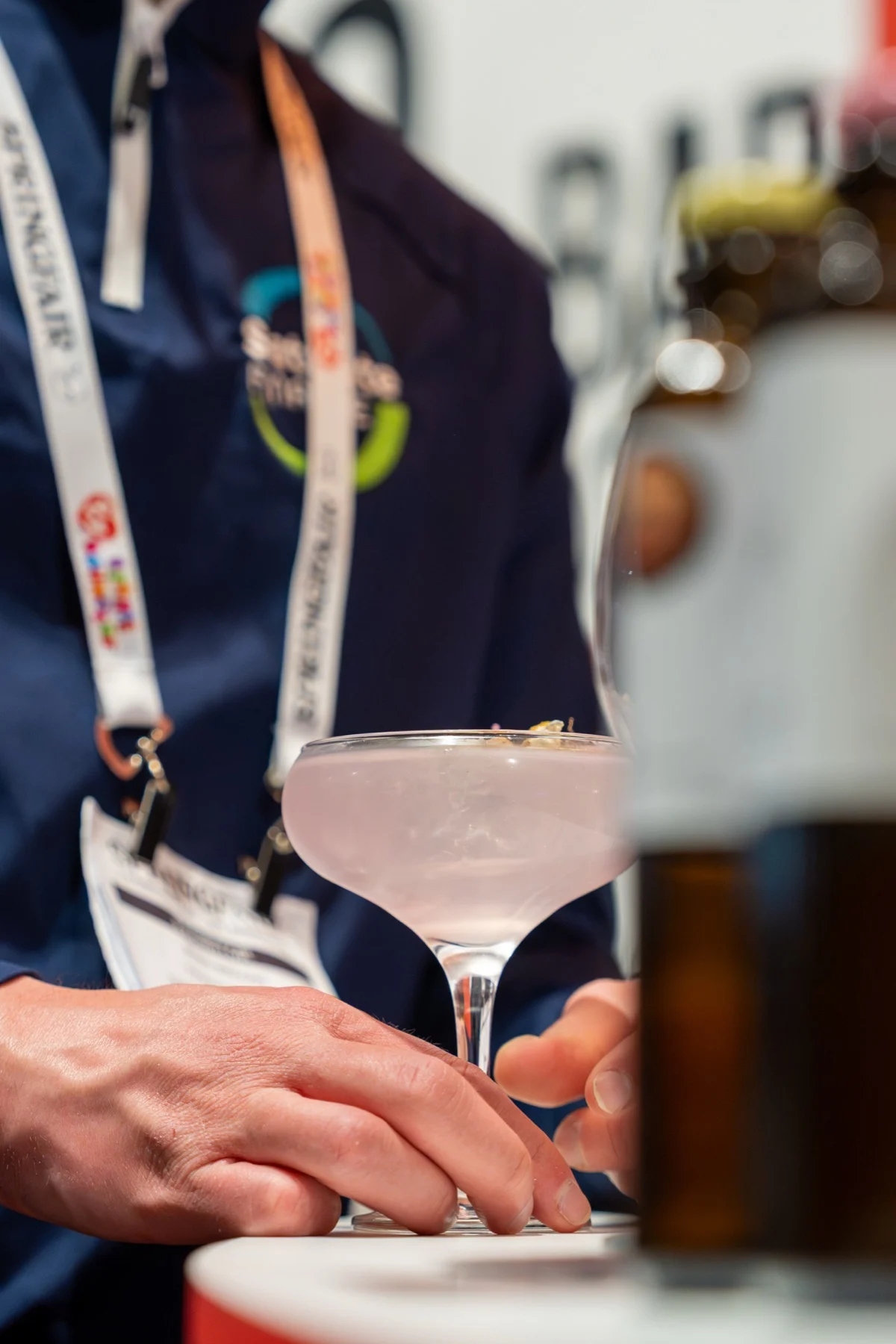 A guest holding a pink cocktail in a coupe glass