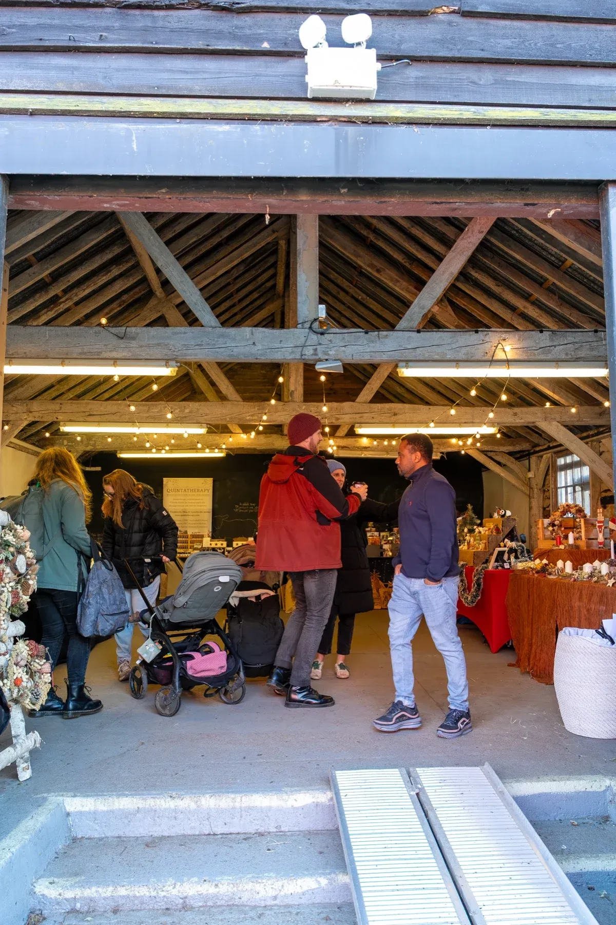 Visitors under the timber roof of a farm market building