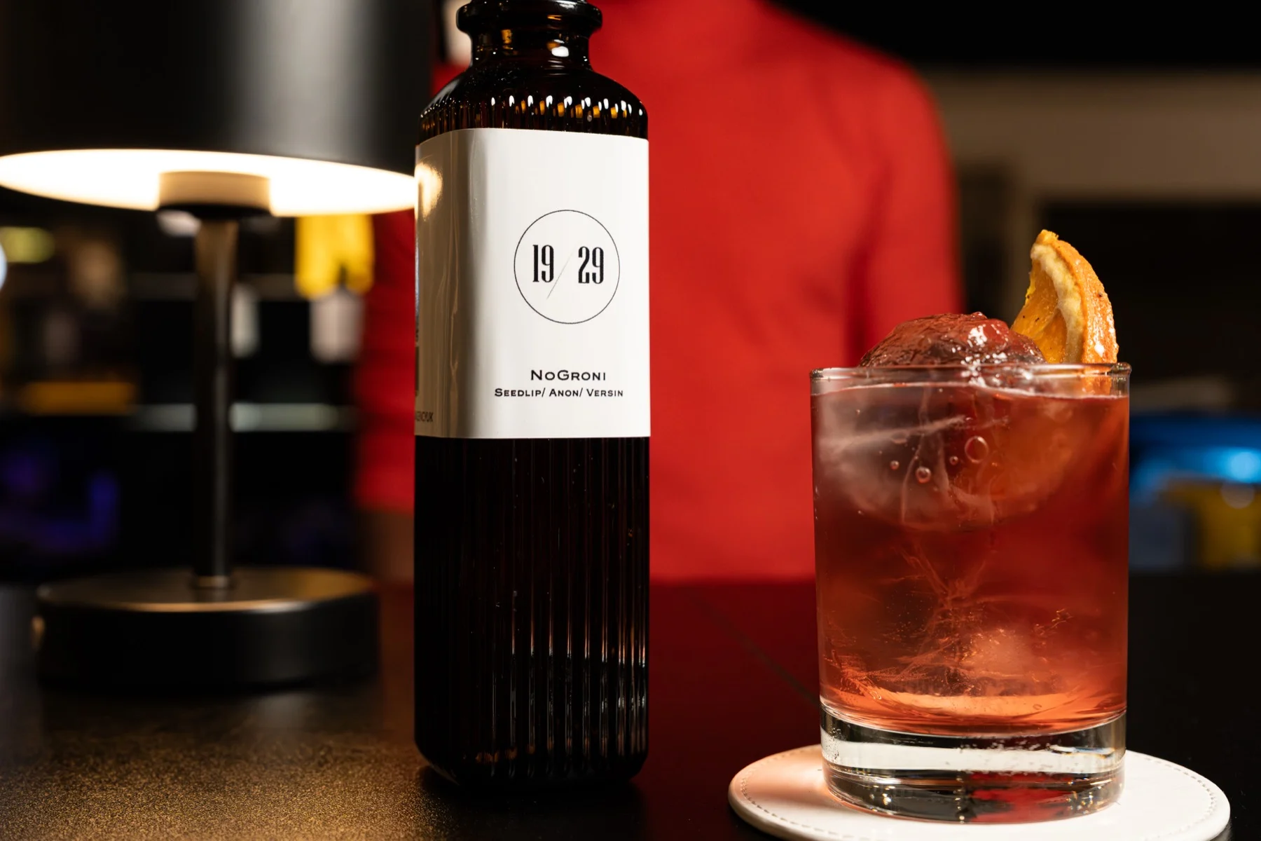 A 19/29 bottle beside a Negroni-style drink with an orange garnish